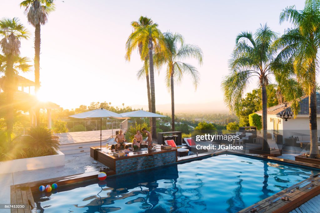 Young group of friends staying in a luxury villa enjoying the hot tub as the sun sets