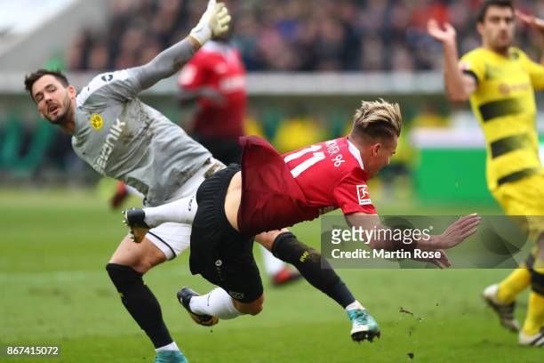 Goalkeeper Roman Buerki of Dortmund fouls Felix Klaus of Hannover, which leads to a penalty for Hannover, during the Bundesliga match between...