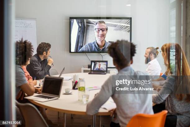 business people having video conference meeting in board room - telefonkonferenz stock-fotos und bilder