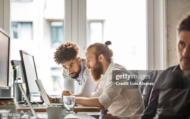 businessmen discussing over laptop in office - developer stockfoto's en -beelden