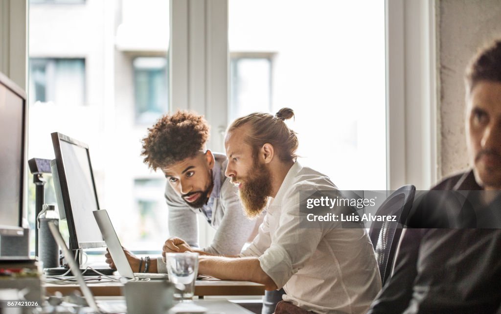 Businessmen discussing over laptop in office