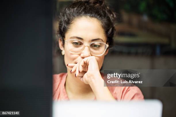 thoughtful businesswoman using computer in office - enfoque fotografías e imágenes de stock