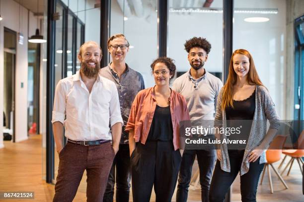 multi-ethnic business people smiling in creative office - fünf personen stock-fotos und bilder