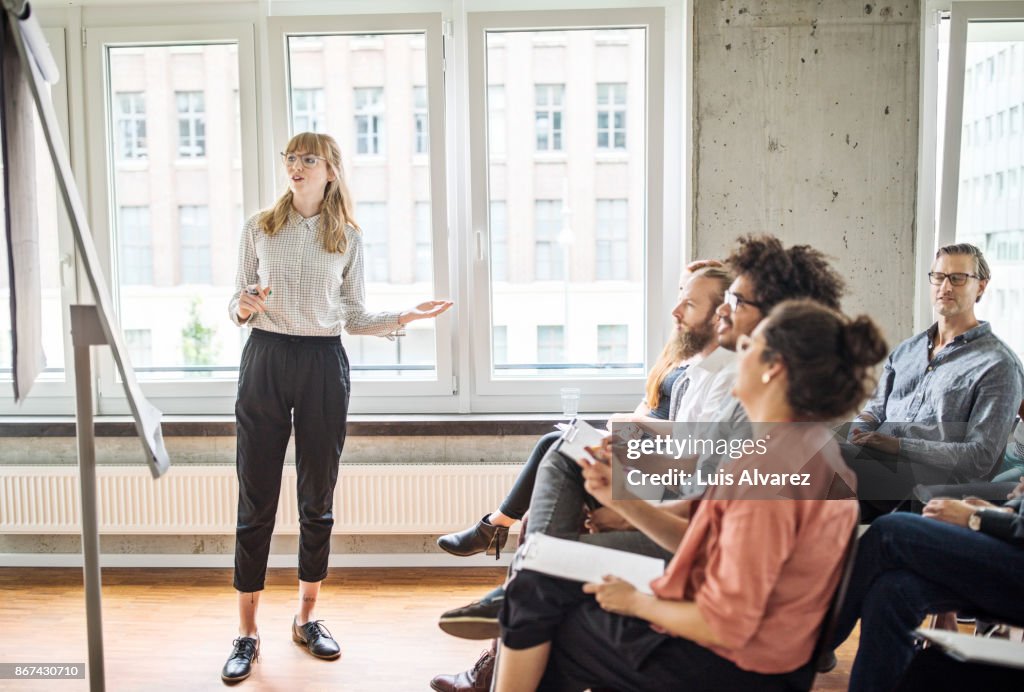 Confident businesswoman giving presentation to coworkers
