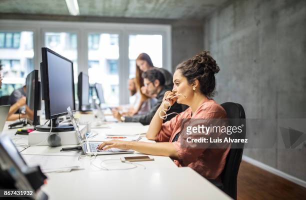 serious businesswoman using laptop in creative office - rosa germanica foto e immagini stock