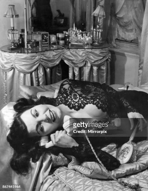 Simone Silva, french actress, answers the telephone in her boudoir, at home Stafford Court, Kensington, London, 20th February 1953.