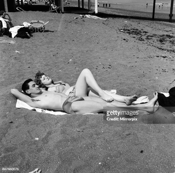 The sunbathing couple of youngsters are Mike Gardner a motor mechanic, being used as a footrest by Valerie Vassallo typist both of Plymouth. They are...
