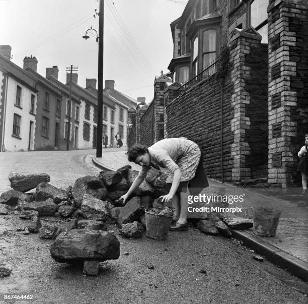 Mrs Annie Berry takes in her coal, which is delivered in a heap in the street. Stanleytown, Rhondda Cynon Taf,Wales, 1st March 1954.