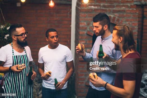 amigos en una barbacoa en el patio trasero - male burger eating fotografías e imágenes de stock