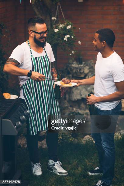 amigos en una barbacoa en el patio trasero - male burger eating fotografías e imágenes de stock