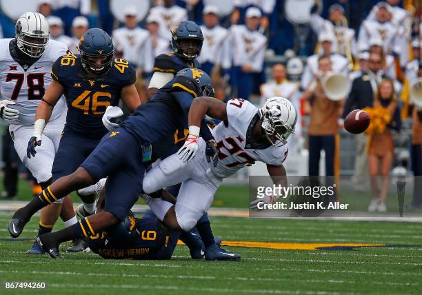 Al-Rasheed Benton of the West Virginia Mountaineers causes J.D. King of the Oklahoma State Cowboys to fumble at Mountaineer Field on October 28, 2017...