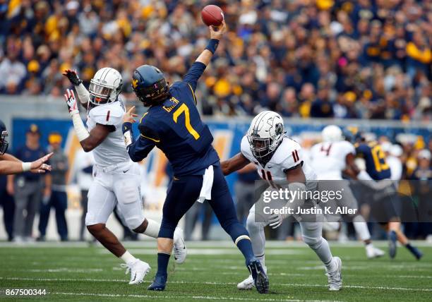 Will Grier of the West Virginia Mountaineers gets a pass on under pressure from Amen Ogbongbemiga of the Oklahoma State Cowboys at Mountaineer Field...