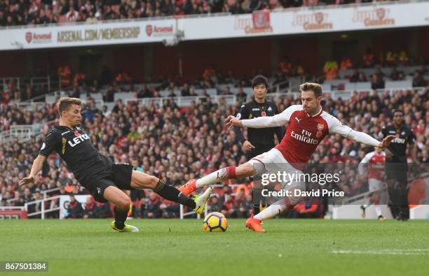 Aaron Ramsey of Arsenal shoots under pressure from Tom Carroll of Swansea during the Premier League match between Arsenal and Swansea City at...