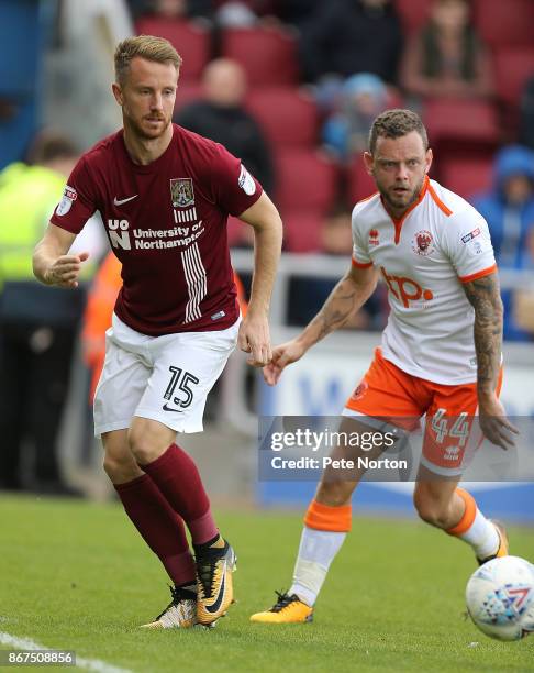 Dean Bowditch of Northampton Town plays the ball watched by Jay Spearing of Blackpool during the Sky Bet League One match between Northampton Town...