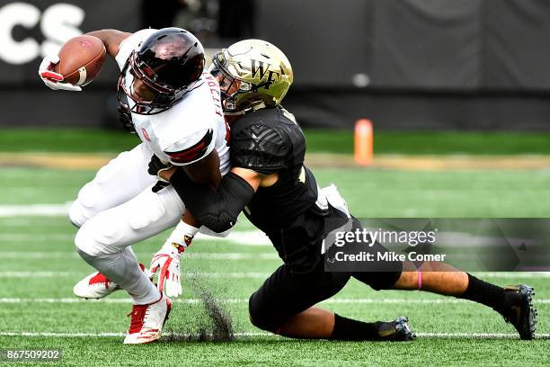 Defensive back Jessie Bates III of the Wake Forest Demon Deacons tackles wide receiver Dez Fitzpatrick of the Louisville Cardinals during the...