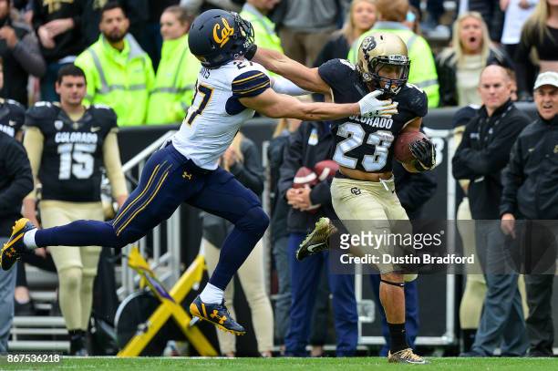 Running back Phillip Lindsay of the Colorado Buffaloes gives a stiff arm to cornerback Ashtyn Davis of the California Golden Bears on a long run in...