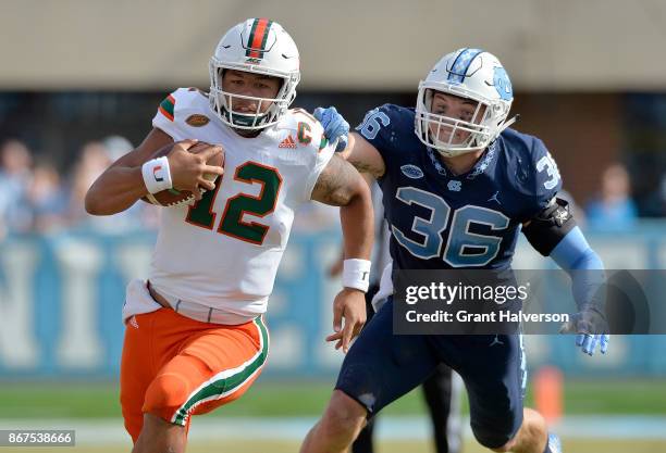 Malik Rosier of the Miami Hurricanes breaks away from Cole Holcomb of the North Carolina Tar Heels during their game at Kenan Stadium on October 28,...