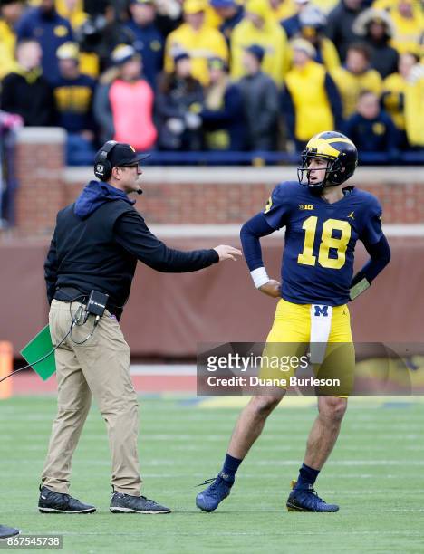 Head coach Jim Harbaugh of the Michigan Wolverines talks with quarterback Brandon Peters of the Michigan Wolverines during the fourth quarter of a...