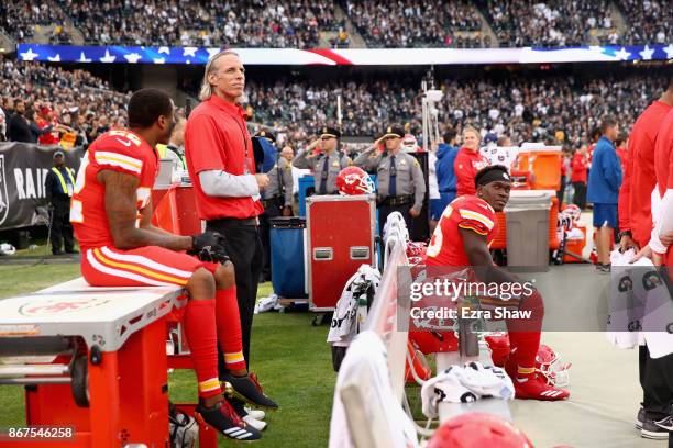 Marcus Peters and Ukeme Eligwe of the Kansas City Chiefs sit on the bench during the national anthem prior to their NFL game against the Oakland...