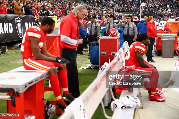 Marcus Peters and Ukeme Eligwe of the Kansas City Chiefs sit on the bench during the national anthem prior to their NFL game against the Oakland...