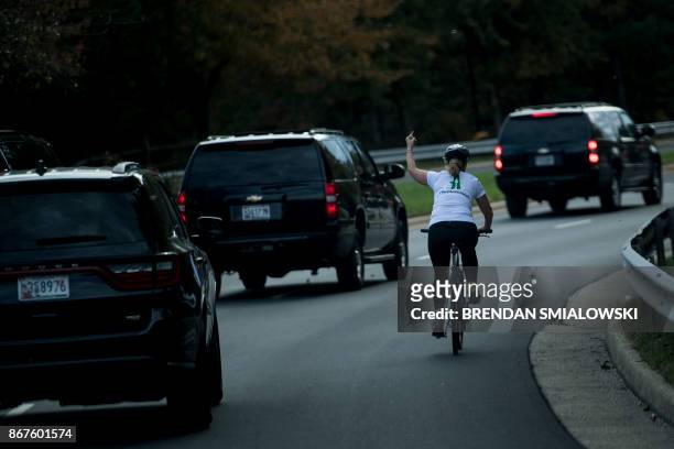 Juli Briskman gestures with her middle finger as a motorcade with US President Donald Trump departs Trump National Golf Course October 28, 2017 in...