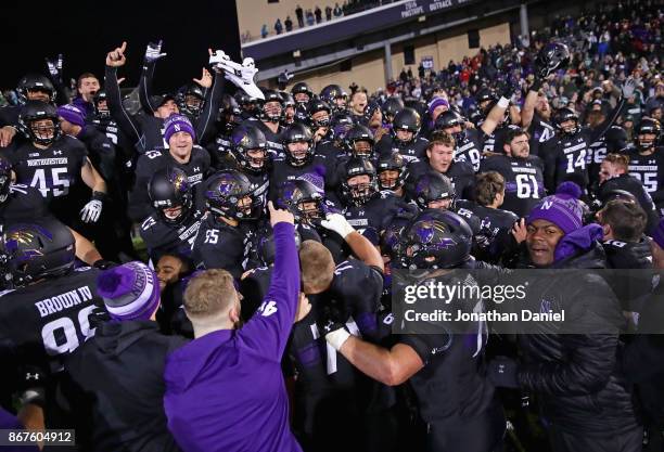 Members of the Northwestern Wildcats celebrate a triple overtime win against the Michigan State Spartans at Ryan Field on October 28, 2017 in...