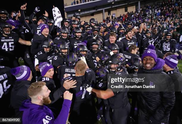 Members of the Northwestern Wildcats celebrate a triple overtime win against the Michigan State Spartans at Ryan Field on October 28, 2017 in...