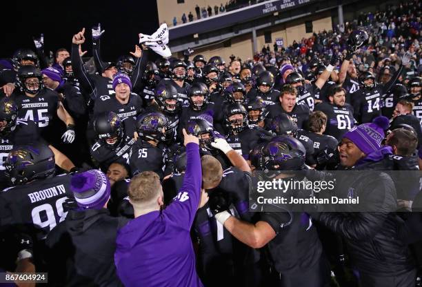 Members of the Northwestern Wildcats celebrate a triple overtime win against the Michigan State Spartans at Ryan Field on October 28, 2017 in...