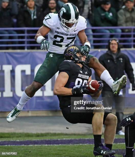 Bennett Skowronek of the Northwestern Wildcats is grabbed by the face mask after making a touchdown catch by Khari Willis of the Michigan State...