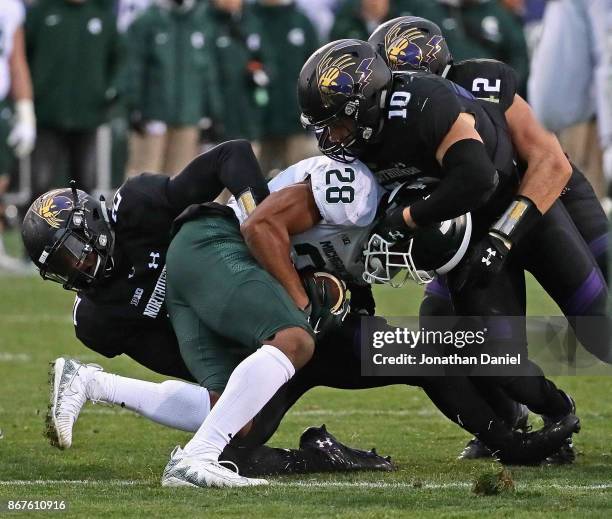 Madre London of the Michigan State Spartans is gang-tackled by Kyle Queiro, Brett Walsh and Paddy Fisher of the Northwestern Wildcats at Ryan Field...