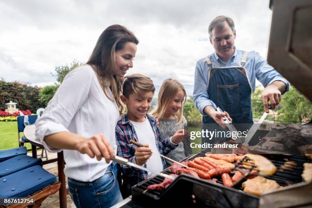 happy family cooking a barbecue outdoors - couple grilling stock pictures, royalty-free photos & images