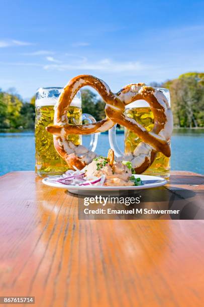 bavarian beer-garden set-up with "obazda" incl. red onions, pretzel and two mass beer - biergarten stock-fotos und bilder