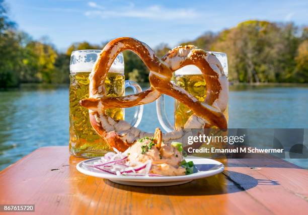 bavarian beer-garden set-up with "obazda" incl. red onions, pretzel and two mass beer - biergarten münchen foto e immagini stock