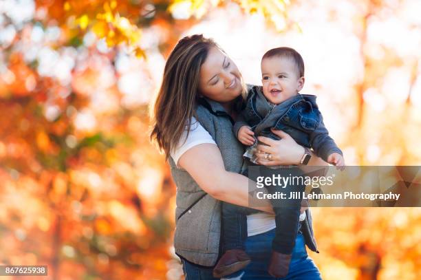 nanny hugs toddler at the iowa state campus in the autumn leaves full of color - nanny smiling stockfoto's en -beelden