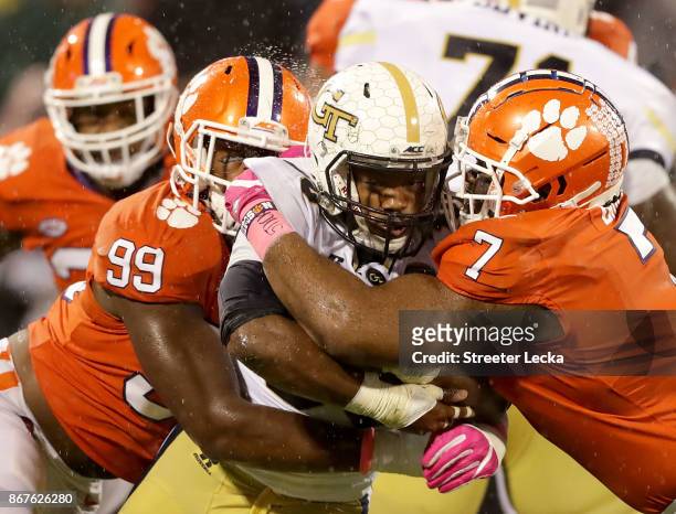 Teammates Clelin Ferrell and Austin Bryant of the Clemson Tigers try to stop KirVonte Benson of the Georgia Tech Yellow Jackets during their game at...