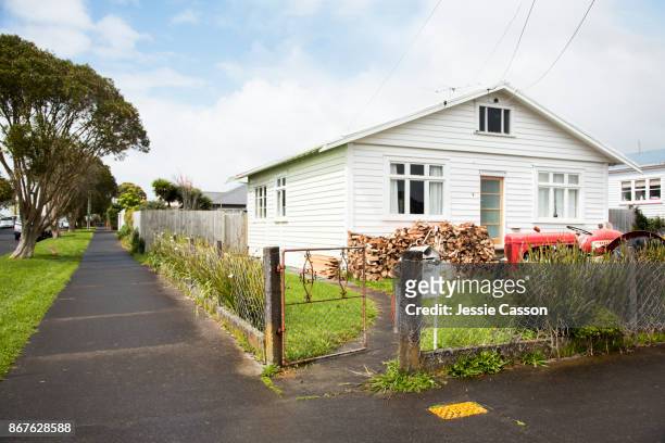 traditional new zealand bungalow with tractor and wood pile in the garden - house new zealand stock-fotos und bilder