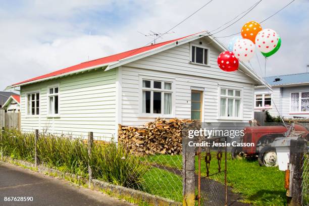 traditional new zealand bungalow with balloons on letterbox and tractor and wood pile in the garden - house new zealand stock-fotos und bilder