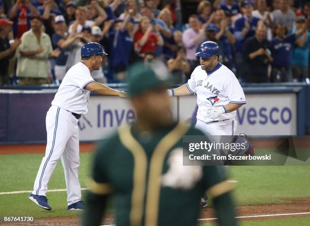 Kendrys Morales of the Toronto Blue Jays is congratulated by third base coach Luis Rivera after hitting a game-winning solo home run in the ninth...