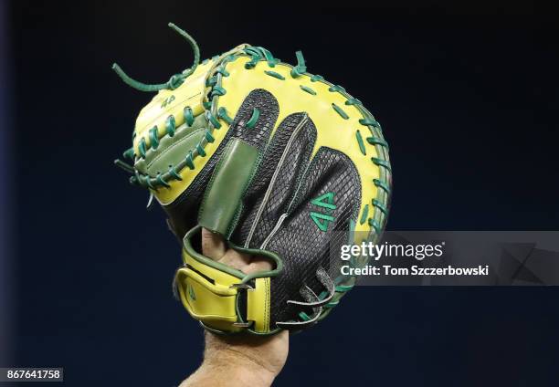 Pitching coach Scott Emerson of the Oakland Athletics wears a green and yellow catcher's glove during batting practice before the start of MLB game...