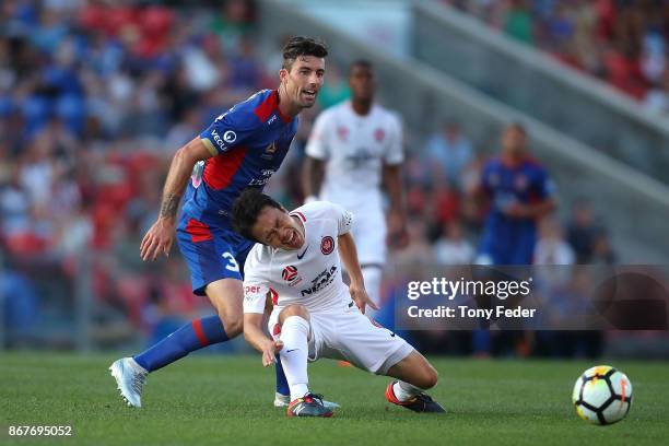 Jason Hoffman of the Jets contests the ball with Jumpei Kusukami of the Wanderers round four A-League match between the Newcastle Jets and the...