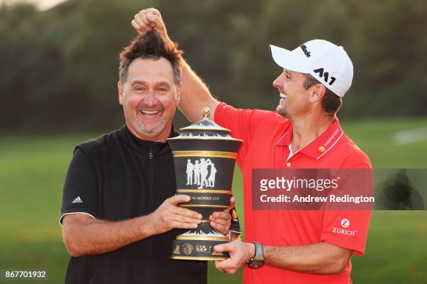 Justin Rose of England celebrates with the Old Tom Morris Cup and caddie Mark Fulcher after finishing 14 under to win the WGC - HSBC Champions at...