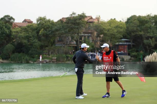 Justin Rose of England celebrates with his caddie Mark Fulcher on the 18th green after finishing 14 under during the final round of the WGC - HSBC...