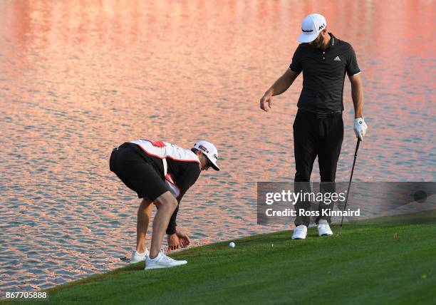 Dustin Johnson of the United States takes a drop on the 18th hole as caddie and brother Austin Johnson assists during the final round of the WGC -...