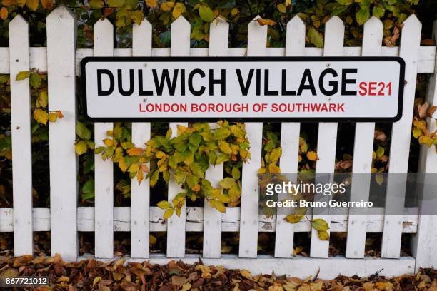 street sign on wooden fence surrounded by autumn coloured leaves - dulwich hamlet stock pictures, royalty-free photos & images