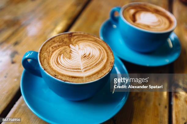 two cups of coffee in blue cups on a wooden table close up - 2 cup of coffee stock pictures, royalty-free photos & images