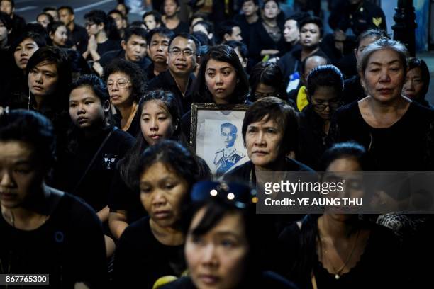 Mourners pray for the late Thai King Bhumibol Adulyadej during the procession transferring the relics and his ashes from the Grand Palace to a local...
