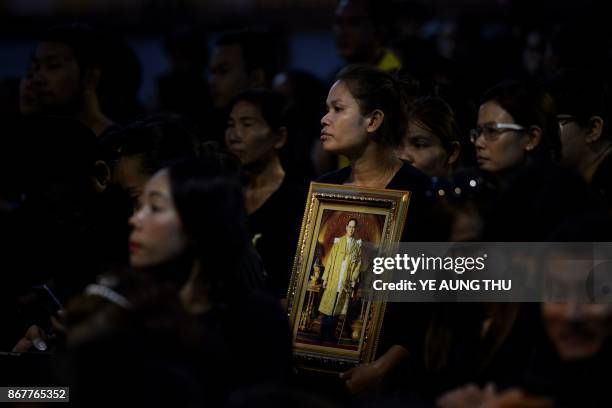 Mourners pray for the late Thai King Bhumibol Adulyadej during the procession transferring the relics and his ashes from the Grand Palace to a local...