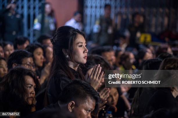 Woman sits up as she watches a procession that took the relics of the late Thai king Bhumibol Adulyadej from the Grand Palace to a local temple in...