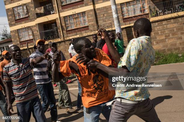 Opposition supporters beat a fellow supporter who threw a rock at a car as they marched down Ngong Road on October 29, 2017 in Nairobi, Kenya....