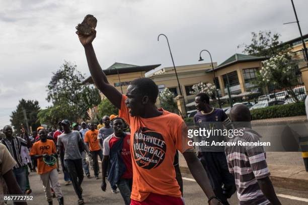 An opposition supporter holds up a rock and cheers as a group march down Ngong Road on October 29, 2017 in Nairobi, Kenya. Tensions remain high in...
